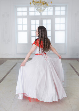 Beautiful woman in white and red medieval dress with crinoline. Back pose