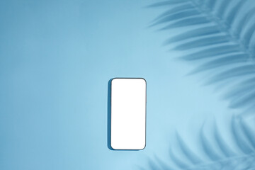 empty blank smartphone mockup with palm shadows on blue background. top view.