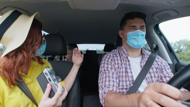 adventures, happy couple in medical masks enjoys family trip with their children and takes memory pictures with retro camera during seed trip by car on summer vacation after quarantine