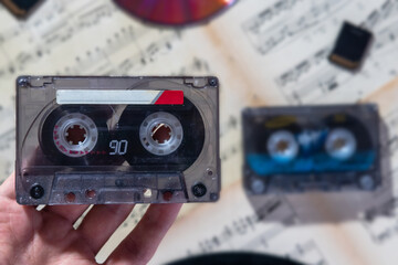 Fototapeta premium a man holds a cassette in his hand against a background of notes, cassettes and a CD