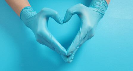 Fototapeta premium A Hand is doing love hand sign and wear surgical gloves or latex gloves on blue background.