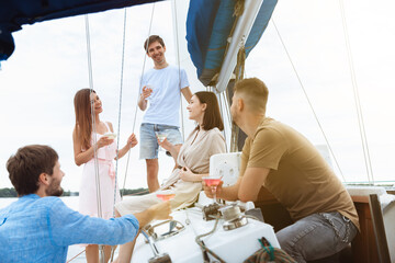 Group of happy friends drinking vodka cocktails at boat party outdoor, cheerful and happy. Young people having fun in sea tour, youth and summer vacation concept. Alcohol, vacation, resting.