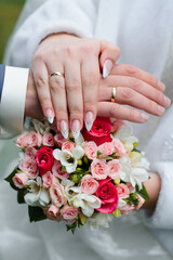 Obraz na płótnie Canvas hands of the bride and groom with wedding gold rings on the background of a beautiful bouquet