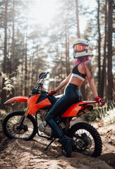 Fototapeta na wymiar Beautiful young woman with pink hair riding on her motorcycle in off road adventure