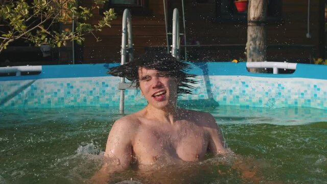 Young man jumping out of the water and shakes the hair out of the water
