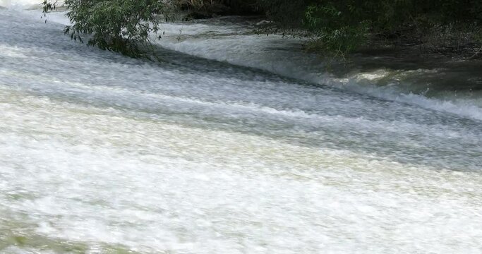 El agua del rio cae por el azud