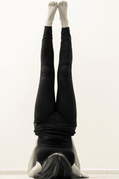 Young woman doing yoga pose. Vertical black and white view of supported legs up the wall Viparita Karani asana
