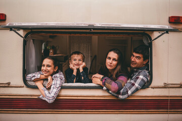 Happy family on a camping trip relaxing in the autumn forest. Camper trailer. Fall season outdoors trip