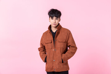 fashion Portrait of Confident handsome young Asian man with keeping hands in pockets of pocket the side eyes looking at camera in isolated on pink blank copy space studio background.