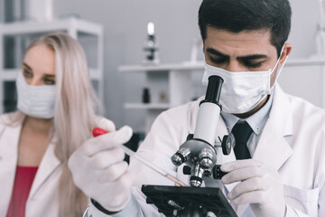 Two scientists are working holding looking at test tube with sample in a chemistry lab scientist or young female and male researcher are doing investigations in Laboratory analysis background