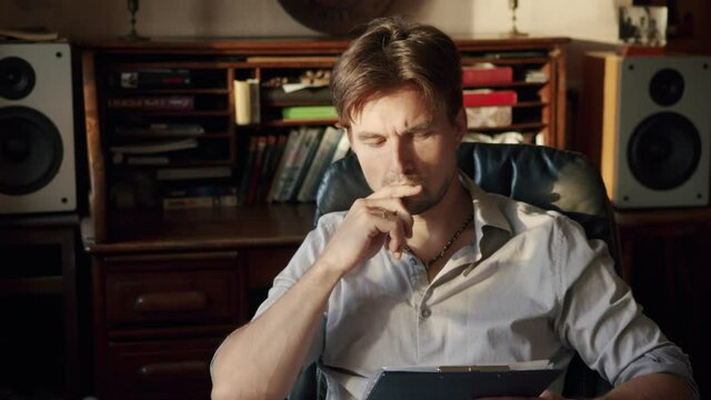 creative screenwriter or writer sitting in his chair thinking about his next big idea and then records it in the sun sitting at home. Medium shot