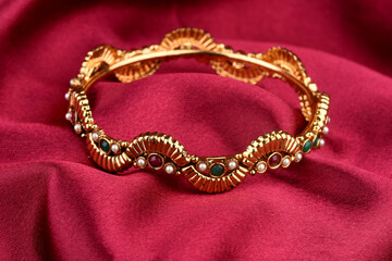 Indian golden Bangles. Bracelet with diamonds and stones on a red satin background, Indian Traditional Jewellery,Style, fashion and design of jewelry