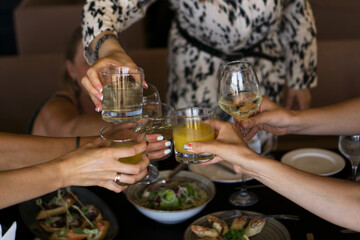 Group of friends enjoying appetizer in bar - Young people hands cheering with wine and tropical fruits cocktails