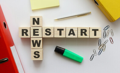 Wooden cubes with words NEWS RESTART on the office desk.