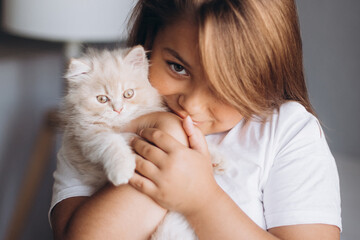 Little girl with small kitten at home. Children and pet 