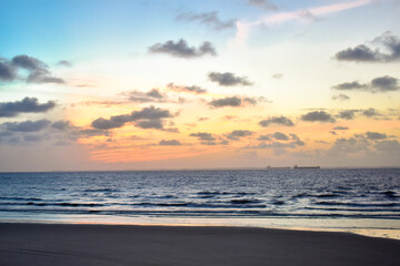 sunset on the beach with boats in the background