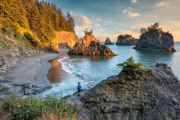 sunset over Samuel Boardman state scenic corridor on the Oregon coast with a hiker standing on the rocks © romylee