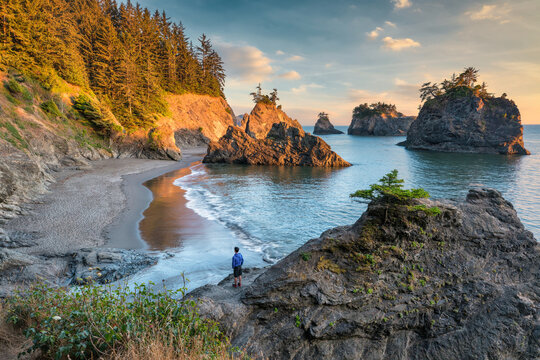 sunset over Samuel Boardman state scenic corridor on the Oregon coast with a hiker standing on the rocks