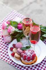 Beautiful and romantic proposal on Saint Valentine's day in Paris - city of love. Bouquet of pink roses, two glasses of wine, macaroons, cake. Eiffel tower on background. Close up copy space. Tonned