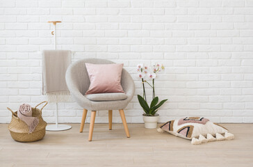 Armchair in living room with orchids, clothes rack and pillows