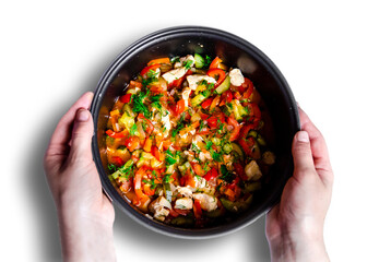 salad noodles and delicious tasty vegetables red bell pepper carrots cucumber dill greens tomato onion shredded fried chicken meat in a pan which hands hold on a white background top view