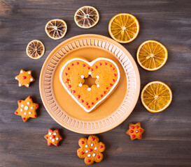 Christmas tasty cookies lie on a saucer on a wooden background. Around the plate lies dried orange and Christmas cookies.
