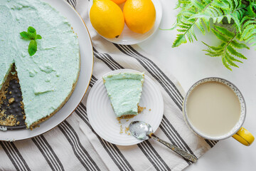 Mint homemade pie with lemon zest on a striped tablecloth. Summer dessert on a white table. Top view. Flat lay.