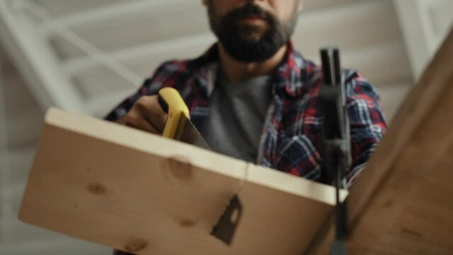 Video of woodworker cutting block of wood using hand saw. Shot with RED helium camera in 8K