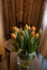 Orange tulips on a table near the window with mocha brown blinds