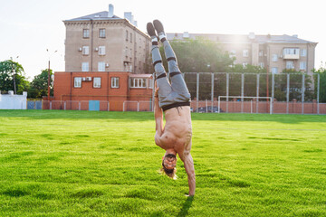 Standing on one hand upside down. Strong, muscular inflated extreme man. Young athlete of Caucasian...