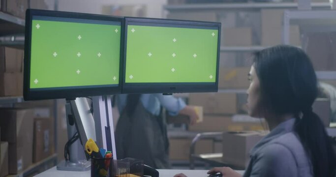 Young woman working at a computer in a distribution center