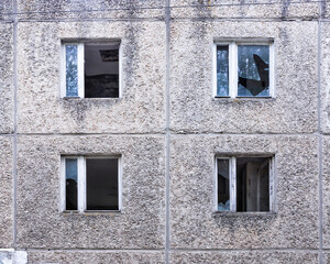 Fototapeta na wymiar Four broken windows in the wall of an abandoned apartment building