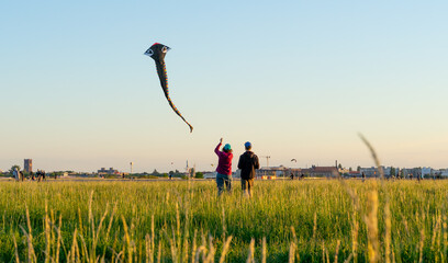 Two men flying kite in puplic park Tempelhofer Feld in Berlin Germany
