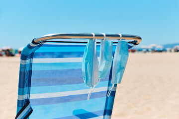 face masks hanging on a deck chair on the beach