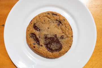 Delicious Belgian Chocolate Chip Cookie on a White Plate on a Wood Table