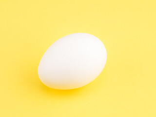 One white chicken egg on a yellow background. Healthy eating concept