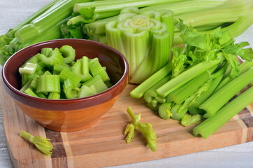 Sliced fresh celery in a clay bowl and Celery stalk on kitchen wooden board