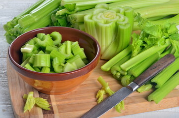 Sliced fresh celery in a clay bowl and Celery stalk on kitchen wooden board