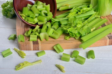 Sliced fresh celery in a clay bowl and Celery stalk on kitchen wooden board