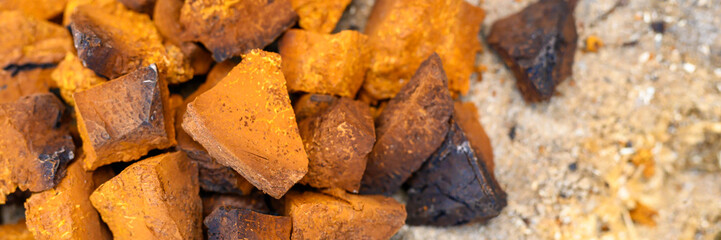 pile pieces of chopped and peeled chaga mushroom birch fungus are stacked on a wooden stump background. step by step. banner