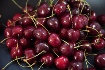 Red fresh cherries on a black background. Drop of water. Close up. The concept of freshness.