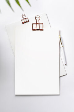 Clipboard with golden clip, blank sheets of paper and pen on white background. Template for branding identity