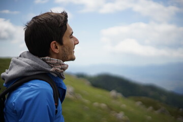 A young male tourist sitting on a rock. He is on the summit of Stara Planina (Balkan Mountains) and enjoying the view.