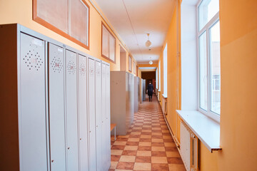 Gray metal outdated lockers in the empty school corridor of the old school
