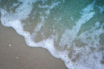 Bubbles waves from the sea on sand beach background 