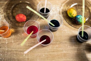 Easter eggs and colored liquid paints on the table for children using dye and painting on white boiled eggs while preparing for Easter