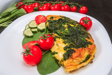 fried eggs with spinach and tomatoes, cucumbers on a white large plate on a black embossed table. top view, copy space, close up