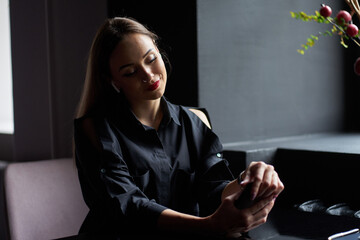 Beautiful blonde cheerful girl with red painted lips wearing trendy black shirt sitting in cafe,...