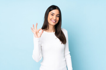 Young caucasian woman isolated on blue background showing ok sign with fingers