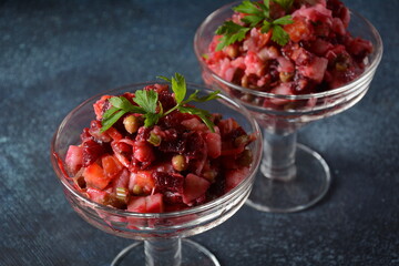 Vinegret or vinaigrette. Traditional Russian red salad with cooked and pickled vegetables, peas, beetroot, in two glass bowls on grey background.
 Vegan healthy dietary food